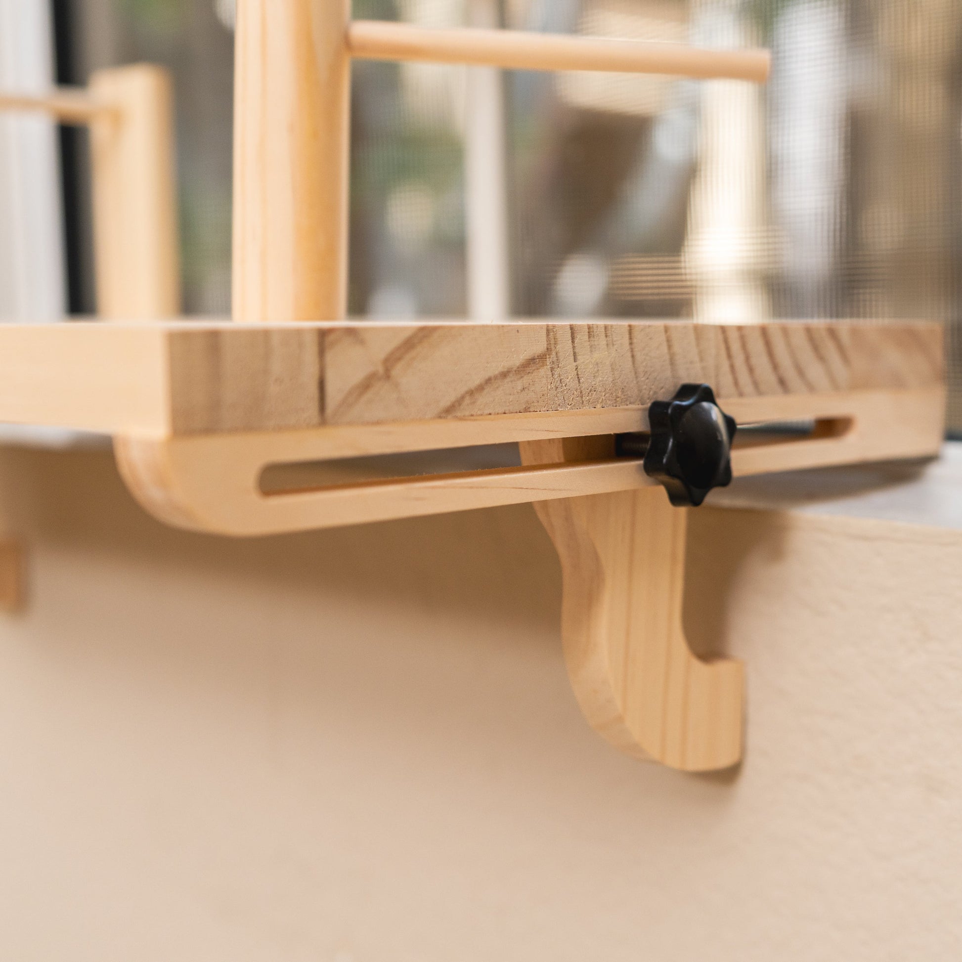 Close-up of the Percheo perch adjustable wooden leg and hand-tightened knob clamped to a window ledge